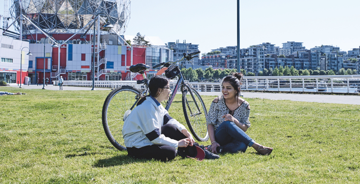two students sitting on grass on a sunny day